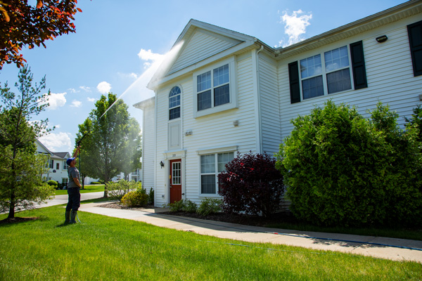 Commercial power washing on apartment building. A Perfect Power Wash technician is cleaning vinyl siding with a power washing wand.