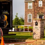 Perfect Power Wash truck in cul-de-sac in front of brick and vinyl home with two technicians working in the distance