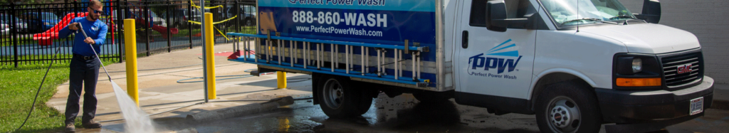 Perfect Power Wash employee washing concrete next to a company vehicle