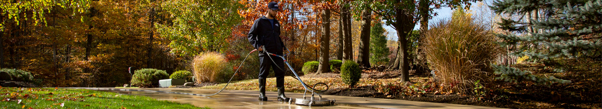 Perfect Power Wash technician surface cleaning a concrete driveway during the fall