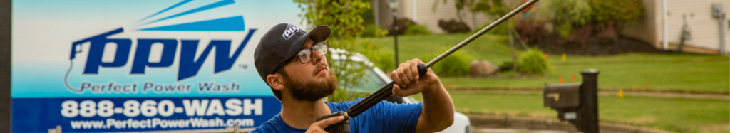 Perfect Power Wash technician soft washing a home with a company vehicle in the background