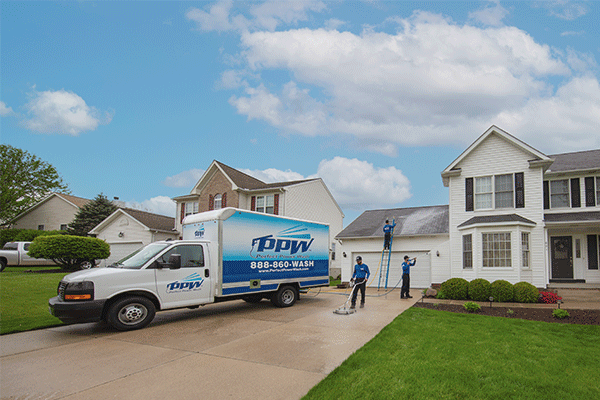 Perfect Power Wash technicians cleaning a roof, driveway, and house